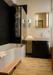 een badkamer met een bad, een wastafel en een spiegel bij Le Vieux Beffroi in Béthune