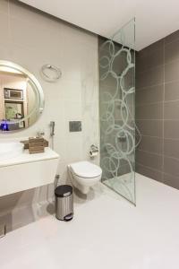 a bathroom with a toilet and a glass shower at Ewaa Express Hotel - Al Hamra in Jeddah