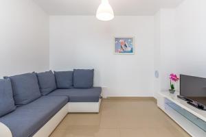Apartments Rina في مالينسكا: غرفة معيشة مع أريكة زرقاء وتلفزيون