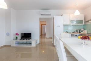 a kitchen with white cabinets and a table with a television at Apartments Rina in Malinska