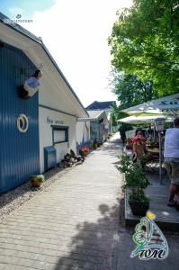 a cobblestone sidewalk next to a blue building with people sitting at tables at Hotel Wald & Meer in Ostseebad Koserow