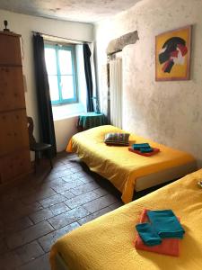 a bedroom with two beds with yellow sheets and a window at CASA LEONE - Apartements im Alto Malcantone in Breno