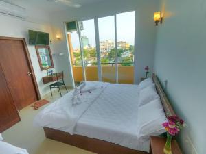 a bedroom with a white bed with a large window at The Den 23 in Maradana