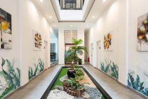 a hallway with plants and paintings on the walls at RedDoorz Premium near Centre Point Mall Medan in Medan