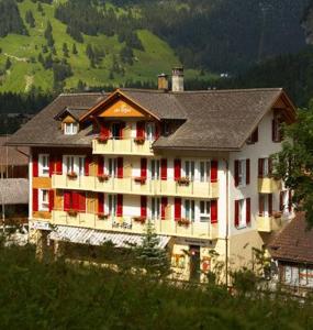 a large building with red and white at Hotel Des Alpes in Kandersteg