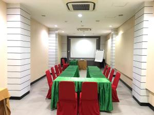 einen Konferenzraum mit einem grünen Tisch und roten Stühlen in der Unterkunft MaxOneHotels.com at Vivo Palembang in Palembang