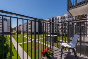 - un balcon d'un immeuble avec une chaise et des fleurs dans l'établissement Airport Bakalarska P&O Serviced Apartments, à Varsovie