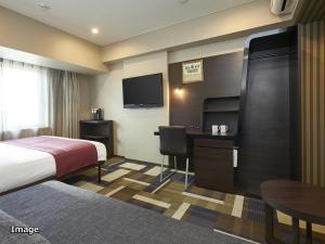 a hotel room with a bed, television and a desk at Hotel Villa Fontaine Kobe Sannomiya in Kobe