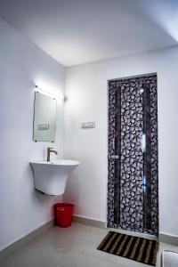 ein Badezimmer mit einem Waschbecken, einem Spiegel und einer Tür in der Unterkunft Hotel Viswa Grand in Kanyakumari