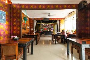 a restaurant with wooden tables and a person sitting at a table at RedDoorz @ Jalan Mojopahit Medan in Medan