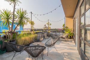 a patio with chairs and tables and palm trees at Beige Poshtels + Netflix in Bangkok