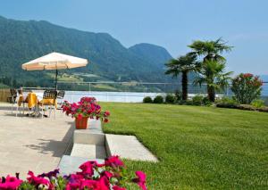 a patio with a table and an umbrella and flowers at Garni Kleefeld in Schenna