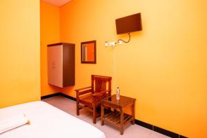 a bedroom with a bed and a chair and a table at Sitiinggil Syariah RedPartner in Tegal