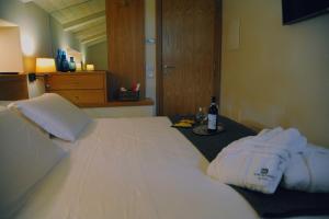 a large white bed with a bottle of wine on it at Dimora del Campo in Matera