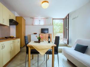 eine kleine Küche mit einem Tisch, Stühlen und einem Sofa in der Unterkunft Apartments Lina 2023 in Rabac