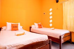 two beds in a room with orange walls at Sitiinggil Syariah RedPartner in Tegal