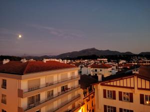 a view of a city at night with the moon at Studio hyper centre avec vue sur les Pyrénées in Saint-Jean-de-Luz