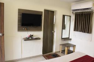 a room with a flat screen tv on a wall at Hotel The New SG in Ahmedabad