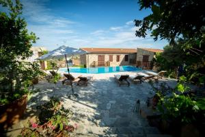 a pool with chairs and an umbrella in a yard at Eveleos Country House in Tochni
