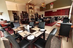 Val Du Charron Wine & Leisure Estate في ويلينغتون: غرفة طعام مع طاولات وكراسي في مطعم