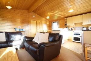 a living room with a leather couch and a kitchen at Concraig Lodge in Crieff