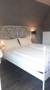 ein weißes Bett mit einem Kopfteil aus Metall und weißen Kissen in der Unterkunft Der Weinladen in Kröv