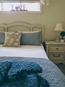 a bedroom with a bed with a blue blanket and a night stand at Little Britton in Wingham