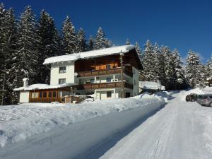 a building in the snow with a road in front at Appartement-Pension Familie Gewessler in Bad Mitterndorf