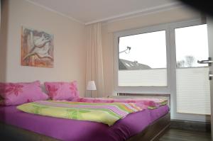 een slaapkamer met een bed met paarse lakens en een raam bij Ferienwohnung Besslich Wattweg 5 in Norden