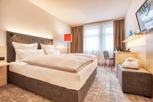 a hotel room with a large bed and a desk at Trans World Hotel Columbus in Seligenstadt