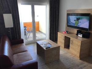 ein Wohnzimmer mit einem Sofa und einem Flachbild-TV in der Unterkunft Ferienwohnung Gipfelstürmer Feldberg - Ski in Ski out, Whirlpool & Infrarotkabine in Feldberg