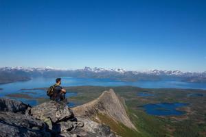 a man standing on top of a mountain overlooking a lake at Tysfjord Hotel in Storjord I Tysfjord