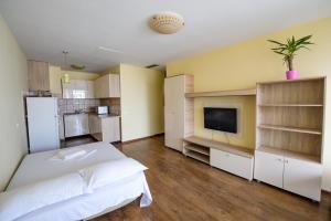 a bedroom with a white bed and a tv at Coralia Luna Park Apartments in Mamaia