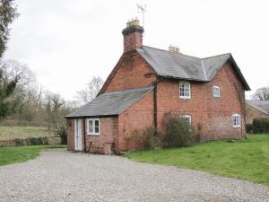 an old red brick building with a chimney on it at Wolvesacre Mill Cottage in Whitchurch