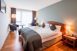 Habitación de hotel con cama, mesa y sillas en Hôtel Rallye & Entrées aux Bains de la Gruyère, en Bulle