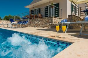 a swimming pool with two wine glasses next to a house at Matušić Guest House in Dubrovnik