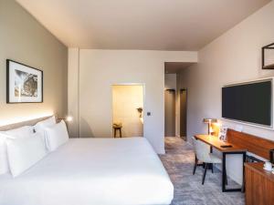 レンヌにあるメルキュール レンヌ サントル プラス ブルターニュのベッド、デスク、テレビが備わるホテルルームです。