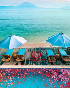 2 chaises et parasols sur un quai donnant sur l'océan dans l'établissement Sunrise Cottage, à Nusa Penida