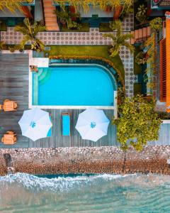 - une vue sur la piscine avec deux parasols dans l'établissement Sunrise Cottage, à Nusa Penida