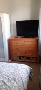 a bedroom with a dresser with a television on it at Constantine Court Homestay in Shepton Mallet