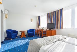 a hotel room with a bed and a desk and chairs at Qubus Hotel Legnica in Legnica