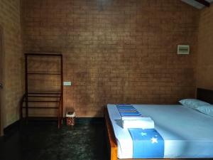 Bett in einem Zimmer mit Ziegelwand in der Unterkunft Oasis Safari Cottage in Udawalawe