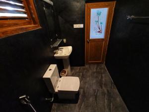 ein Badezimmer mit einer weißen Toilette und einem Waschbecken in der Unterkunft Oasis Safari Cottage in Udawalawe