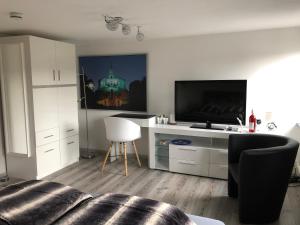 a white living room with a tv and a couch at "An der Lindenberganlage" in Melsungen