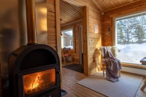 einen Holzofen in einer Blockhütte mit einem Fenster in der Unterkunft Mökki - The White Blue Wilderness Lodge in Inari