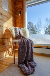 a blanket sitting on a chair in a room with a window at Mökki - The White Blue Wilderness Lodge in Inari