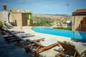 a group of lounge chairs next to a swimming pool at Eveleos Country House in Tochni