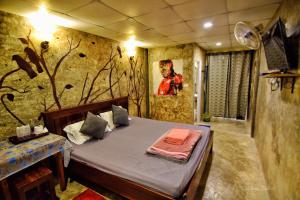 1 dormitorio con 1 cama con una pintura en la pared en อีต่องโฮมสเตย์, en Thong Pha Phum