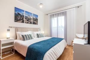 ein weißes Schlafzimmer mit einem Bett und einem TV in der Unterkunft Villa Simone by Intiholidays in Quarteira