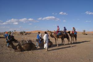 a group of people riding on horses in the desert at Enjoy Moda Camp Merzouga tours- Camel sunset sunrise Quad Sunboarding ATV in Merzouga